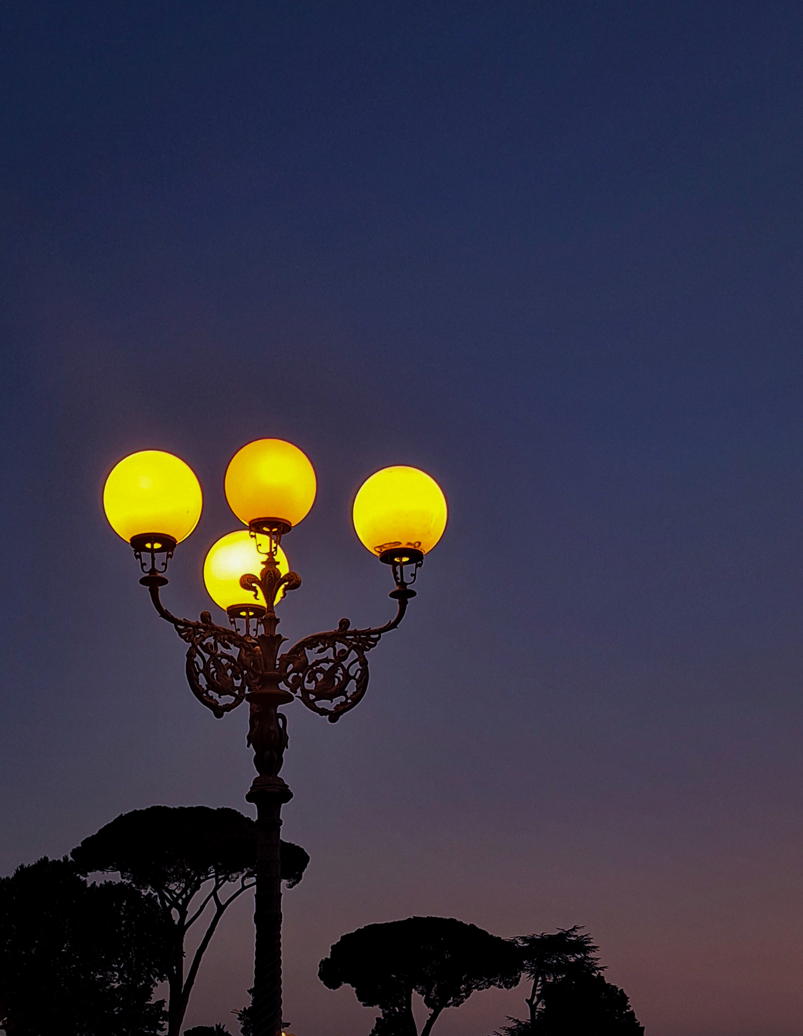 Firenze by night -- Mise en valeur des lampadaires illuminant une place à Florence, en Italie, sous la lumière violacé et orangé du soleil couchant. Cette scène capture l'atmosphère magique de la ville alors que les lumières urbaines commencent à s'allumer et que le ciel se teinte de couleurs vibrantes.