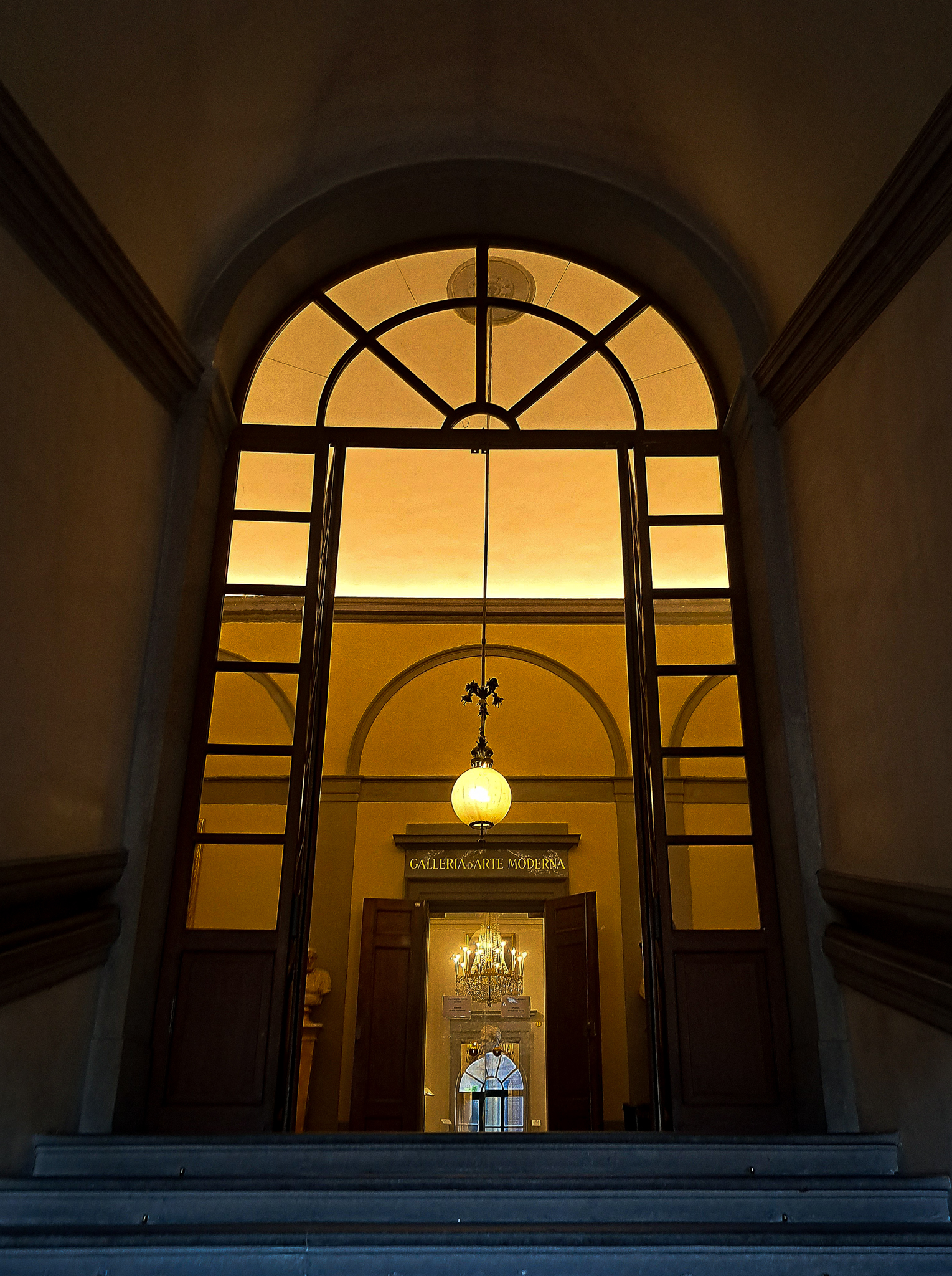 Architecture -- Prise de vue en contre-plongée d'un cadran de porte d'un palais italien. La simplicité du cadran laisse entrevoir la pièce derrière, baignée d'une lumière jaune douce. Ce détail minimaliste capture l'atmosphère chaleureuse et authentique de l'intérieur de ce palais historique.