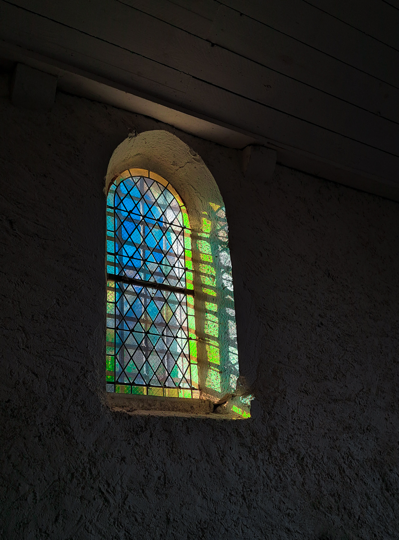 Vitrail unique d'une petite chapelle située dans les hauteurs de Claix. Le soleil se reflète dans la pièce à travers ces morceaux de verre, se teintant de mille et une couleurs. C'est un spectacle enchanteur où la lumière danse à travers les motifs du vitrail, créant une ambiance paisible dans cet espace sacré.